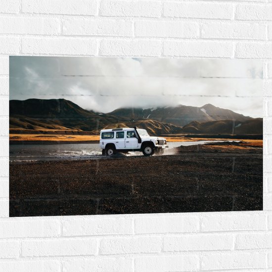 WallClassics - Muursticker - Witte Grote Auto door het Water bij het Berglandschap - 90x60 cm Foto op Muursticker