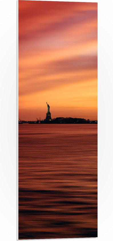 WallClassics - PVC Schuimplaat - Vrijheidsbeeld in New York van Ver met Zonsondergang - 30x90 cm Foto op PVC Schuimplaat (Met Ophangsysteem)