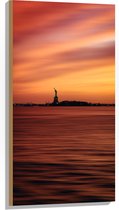 WallClassics - Hout - Vrijheidsbeeld in New York van Ver met Zonsondergang - 50x100 cm - 9 mm dik - Foto op Hout (Met Ophangsysteem)