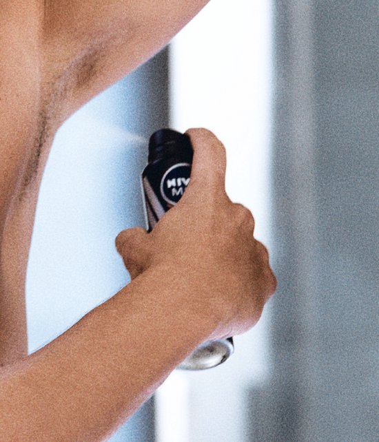 Hand spuit NIVEA MEN deodorant op de oksel.
