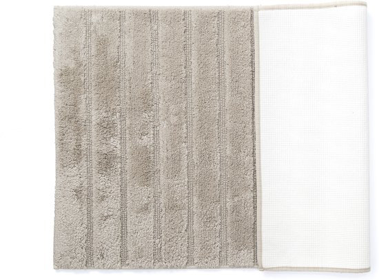 Zandkleurige badmat met fijne ribbels, opgerold om de antislip onderkant te tonen.