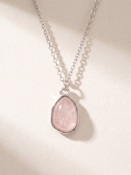 Zilverkleurige ketting met een roze, druppelvormige rozenkwarts hanger met onregelmatige rand.