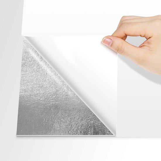 Een hand trekt een zilverkleurige, glanzende sticker van een witte achtergrond.
