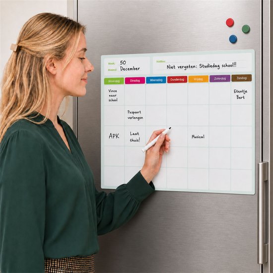 Magnetische weekplanner op een koelkast, met een vrouw die een afspraak schrijft. Dagen van de week in kleur.