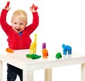 Enfant en bas âge joyeux portant des vêtements rouges jouant avec des animaux de safari jouets.