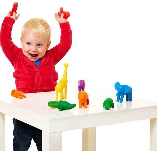 Enfant en bas âge joyeux portant des vêtements rouges jouant avec des animaux de safari jouets.