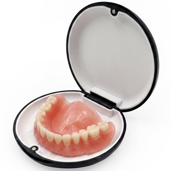 Een prothese met roze tandvlees en witte tanden in een zwart en wit bewaardoosje.