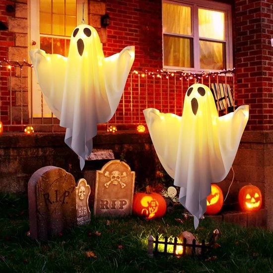 Twee hangende spoken versierd met LED-verlichting, met gezichten, naast Halloween-grafstenen en pompoenen.
