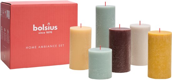 Bolsius Home Ambiance Set met zes rustieke kaarsen in kleuren zoals lichtblauw, geel, bruin en beige, naast een rode doos.