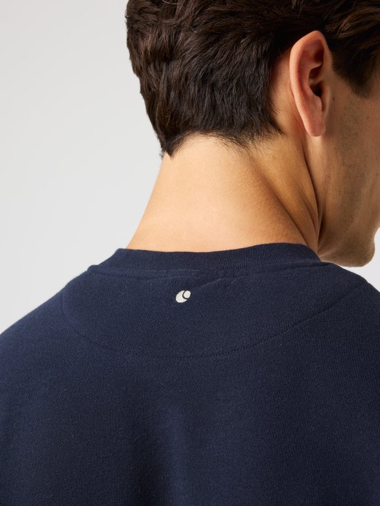 Detail van de achterkant van een donkerblauwe sweater met op de nek een klein wit logo.