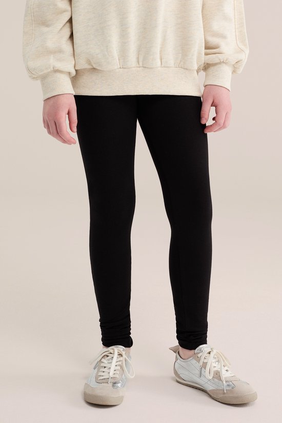Gedetailleerde weergave van zwarte legging met sneakers.