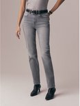 Model in een grijs t-shirt, grijze jeans met zwarte riem en zwarte laarzen.