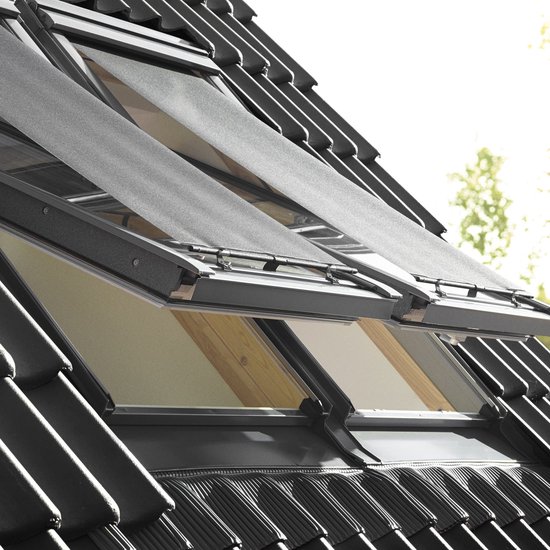 Deux stores pare-soleil noirs pour fenêtres de toit, montés sur un toit en pente avec des tuiles grises.