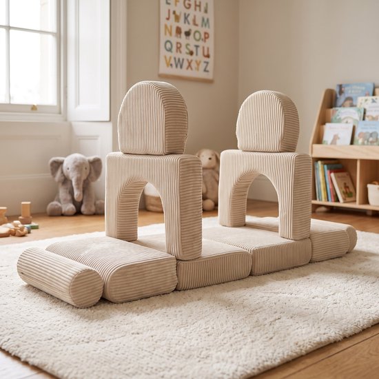 Beige corduroy speelgoed blokken op een kleed, met bogen en kussens.