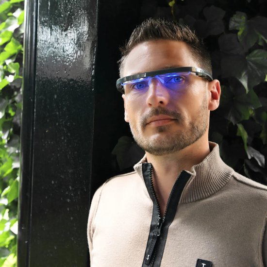 Man draagt bril met blauw licht, kijkt naar de camera.
