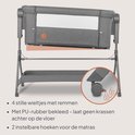 Grijze co-sleeper met een mand onderaan en wieltjes met remmen.