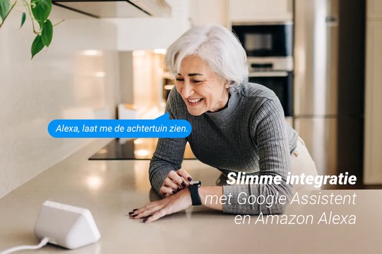 Een lachende vrouw met grijs haar kijkt naar een slimme speaker, terwijl de tekst "Alexa, laat me de achtertuin zien." verschijnt.