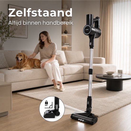 Zwarte steelstofzuiger staat zelfstandig op een beige tapijt, met een vrouw en hond op de bank. Een vergrote cirkel toont de 90° kantelbare kop. "Zelfstaand Altijd binnen handbereik".