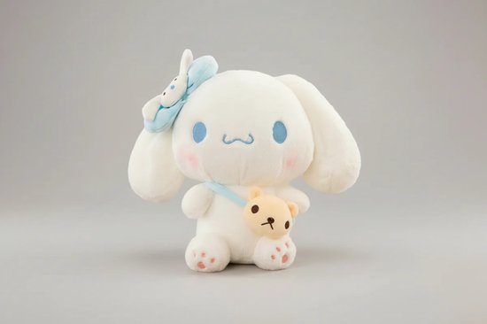 Wit Cinnamoroll pluche met blauwe strik en teddybeer tasje. Blauwe ogen en roze wangen.