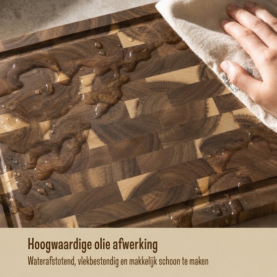 Une main essuie l'eau d'une planche à découper en bois avec un tissu à tissage grossier. La planche a un motif en blocs.