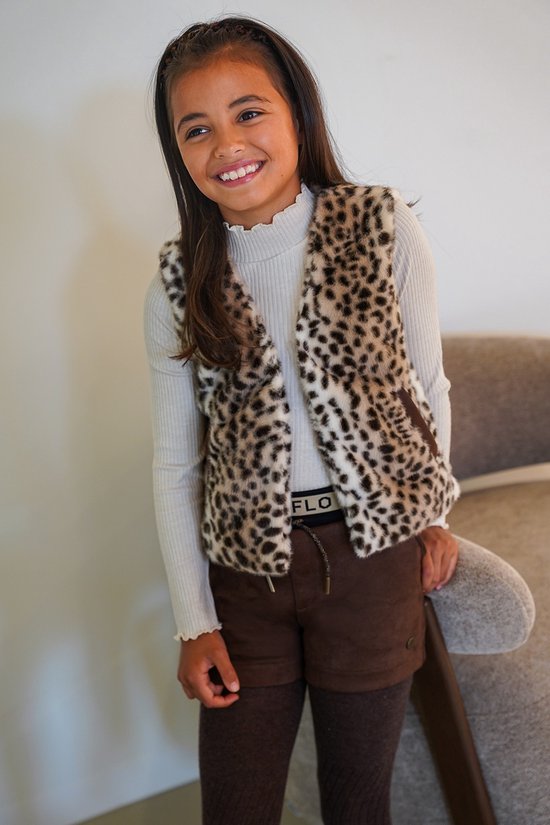 Meisje met luipaardprint bodywarmer, lichtgrijze coltrui, bruine shorts en bruine panty.