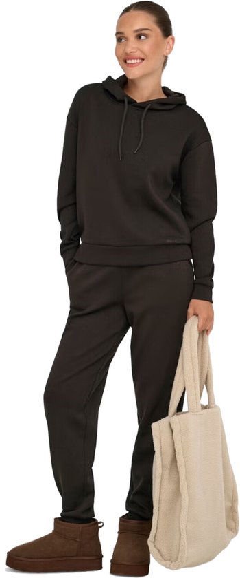 Vrouw met een donkere hoodie en joggingbroek, draagt een beige teddy shopper.