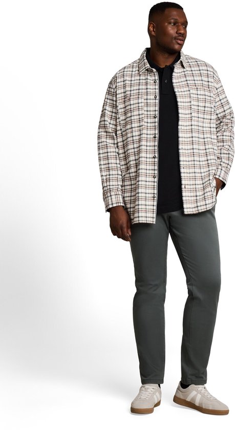 Model met donker olijfgroene chino, normale pasvorm, met gestreept hemd over een zwart poloshirt.