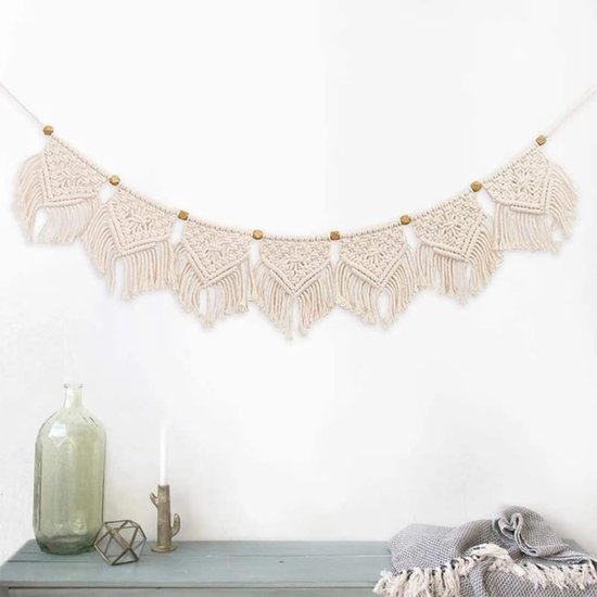 Witte macramé slinger met franjes en houten kralen, een decoratief object in een minimalistische setting.
