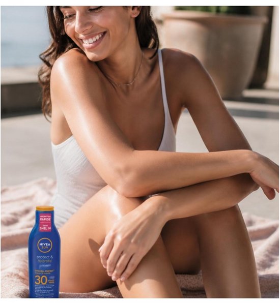 Een lachende vrouw met een witte badpak op een handdoek met een fles Nivea Sun protect & hydrate SPF 30.