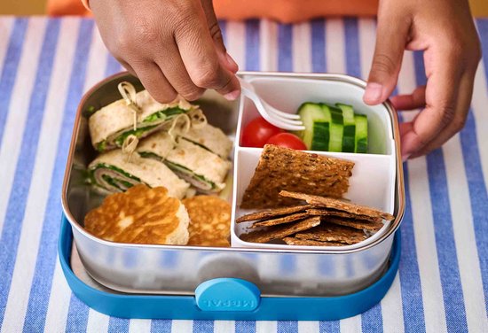 Een kind opent een RVS lunchbox met rolletjes, pannenkoekjes, cherrytomaatjes, komkommer en crackers.