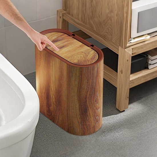 Hand die op het deksel van een ovale houten afvalbak drukt.