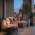 Witte Pilia tafellamp op een bijzettafel op een balkon bij een loungeset met uitzicht op de stad.