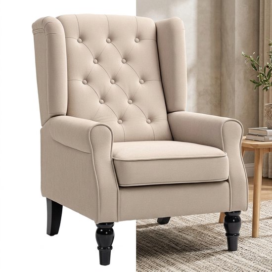 Een beige fauteuil met knoopgestikte rugleuning en zwarte gedraaide poten, geplaatst op een geblokt vloerkleed.