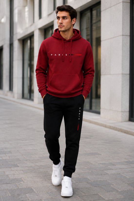 Man draagt bordeauxrode hoodie met 'PARIS'-print en zwarte joggingbroek met 'PARIS'-print.