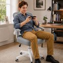 Een man zit op een grijze bureaustoel met witte armleuningen en een wit onderstel, terwijl hij een smartphone vasthoudt.