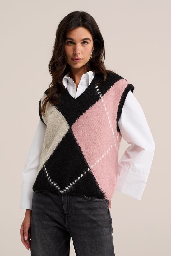 Model draagt een gebreide spencer met ruitpatroon in roze, zwart en beige.
