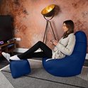 Vrouw zit op een donkerblauwe zitzak met voetenbankje, spelend met een controller.