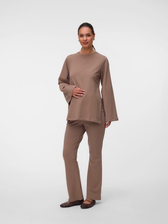 Model in een volledige set van bruine zwangerschapskleding met bijpassende trui en uitlopende broek.