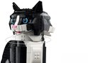 Close-up van de zwart-witte LEGO kat met blauwe ogen en roze snuit.