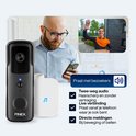 Finetech videodeurbel naast witte binnenbel. Man op smartphone kijkt naar beeld van jongeman.