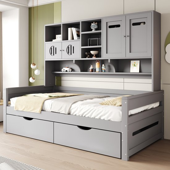 Grijze bedombouw met bovenbouw vol kasten en open vakken, in een slaapkamer met beddengoed.