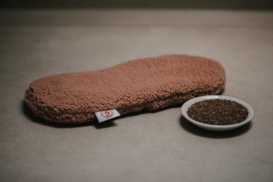 Bruin teddy pluche warmtekussen met een schaaltje lijnzaad ernaast.