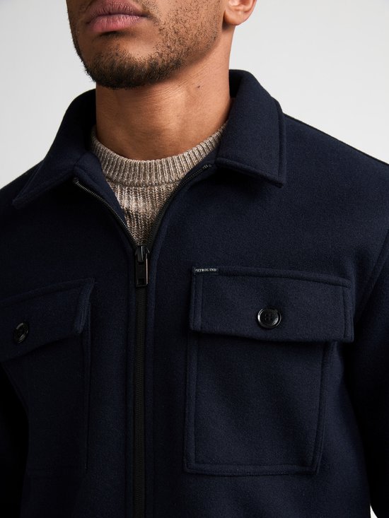 Close-up van de kraag en borstzak van het donkerblauwe Petrol Industries overshirt met rits.