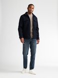 Model draagt een donkerblauw Petrol Industries overshirt over een beige trui en blauwe jeans.