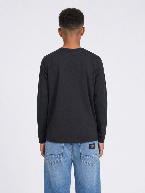 Jongen met een zwarte longsleeve van de achterkant en distressed jeans.