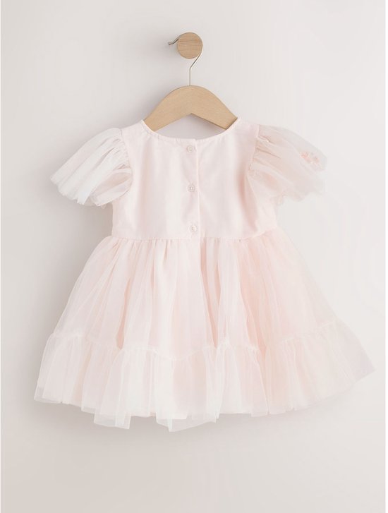 Roze mesh feestjurk met korte, pofmouwen en ruches, hangend aan een houten kleerhanger.