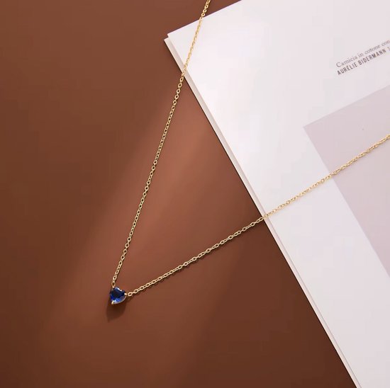 Gouden ketting met een hartvormige, diepblauwe edelsteen.
