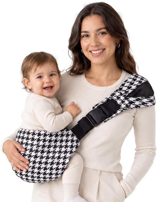 Femme joyeuse portant un porte-bébé avec un motif pied-de-poule noir et blanc.