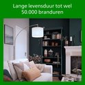 Moderne woonkamer met bank, boekenkast en booglamp die koele verlichting biedt.