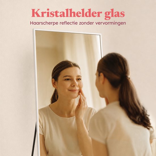 Een vrouw raakt haar gezicht aan terwijl ze in een spiegel kijkt. Tekst: Kristalhelder glas.